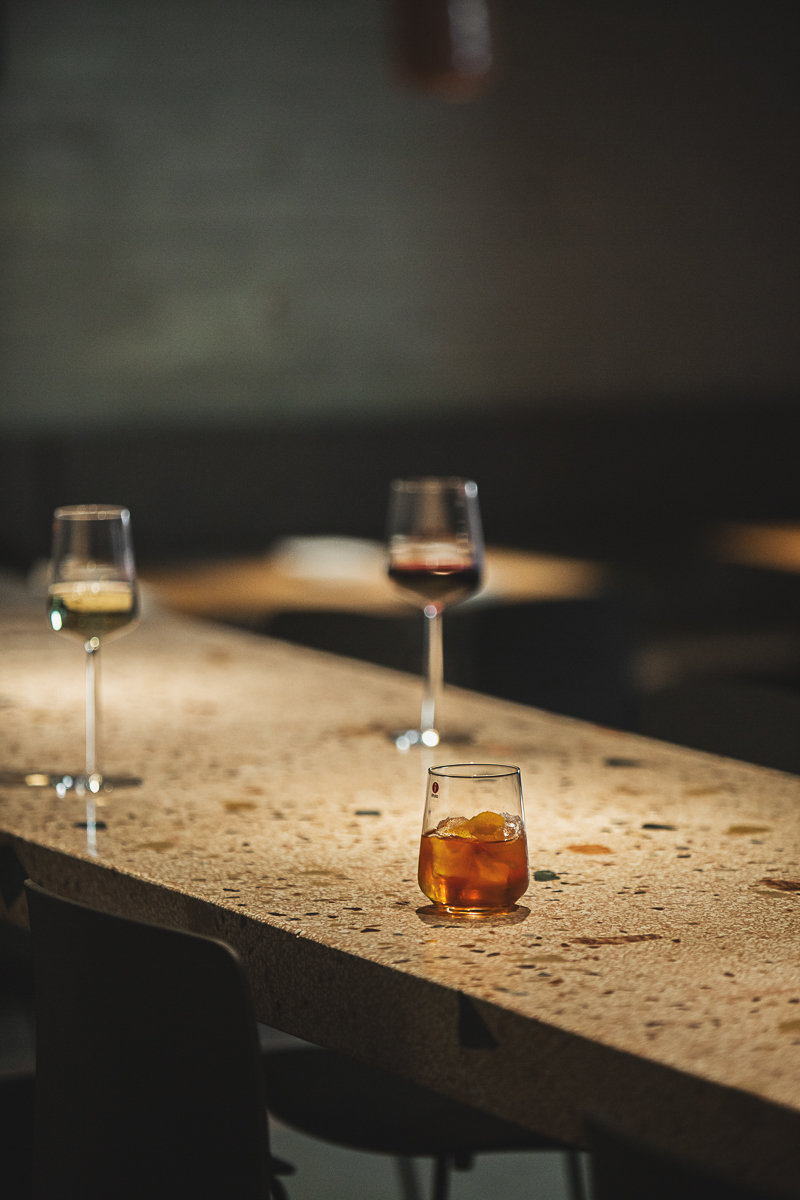 Stemmige sfeerfoto van twee wijnglazen en een tumbler op een terrazzobar